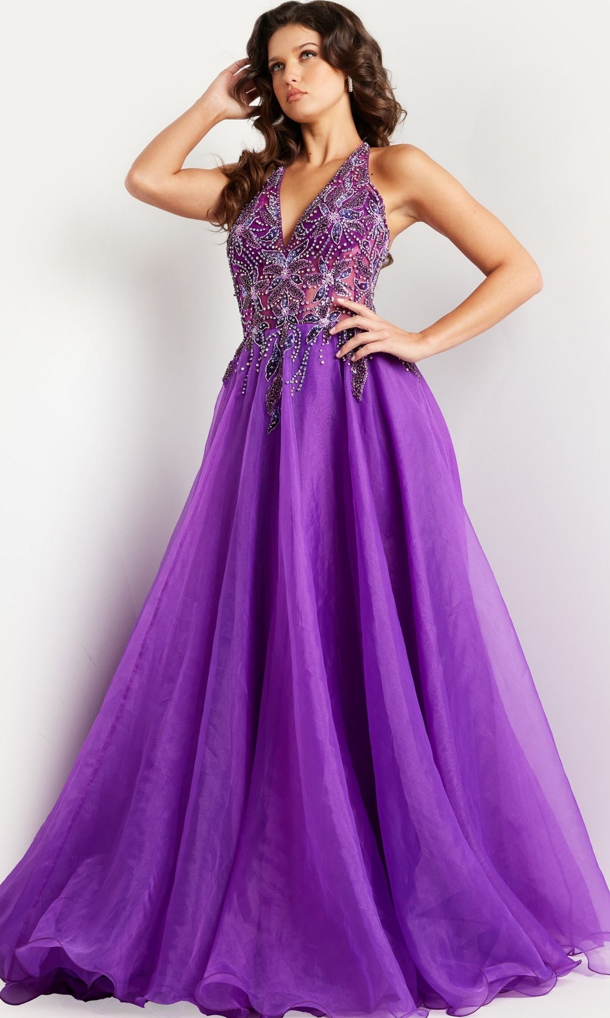 A woman poses in the Jovani Long Organza Halter Prom Ball Gown 25964, featuring a fitted embellished bodice and a flowing floor-length skirt.
